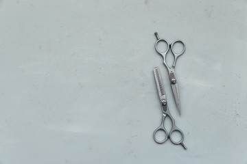Pair of stylish professional barber scissors on gray wooden background. Copy space. Top view. Flat lay