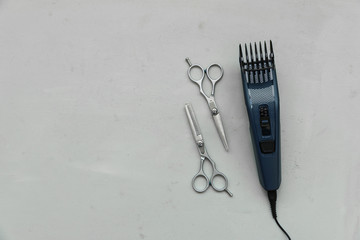 Hair trimmer and pair of stylish professional barber scissors on gray wooden background. Copy space. Top view. Flat lay