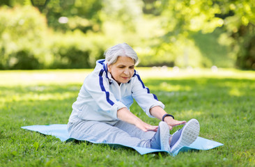 fitness, sport and healthy lifestyle concept - happy smiling senior woman exercising on mat at...