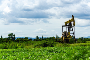 Oil rig pumps oil against the backdrop of mountains and overcast sky. Beautiful mountain landscape....