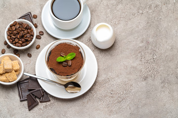 Classic tiramisu dessert in a glass, coffee, chocolate, cream and sugar on concrete background