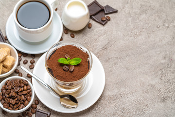 Classic tiramisu dessert in a glass, coffee, chocolate, cream and sugar on concrete background