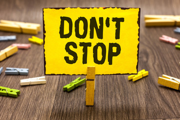 Text sign showing Don t not Stop. Conceptual photo Continue what had been doing without rendering a delay Clothespin holding yellow paper note several clothespins wooden floor - obrazy, fototapety, plakaty