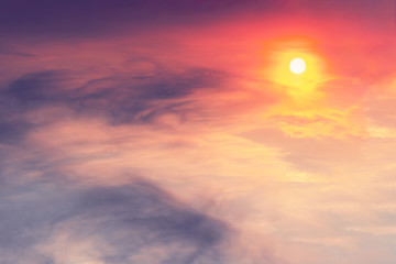 The sunset in the sky is pink-orange with purple clouds in the form of stains on which the sun shines. Landscape concept.
