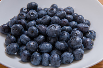 Clean freshly picked blueberries on white plate - close up studio shot. ( Ingredients:  Antioxidants , Vitamin C, Antioxidant)