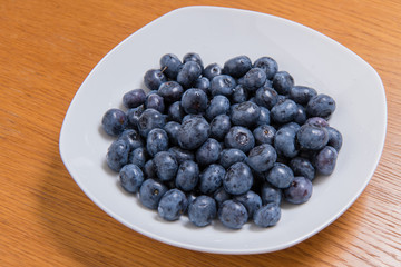  Clean freshly picked blueberries on white plate - close up studio shot. ( Ingredients:  Antioxidants , Vitamin C, Antioxidant)