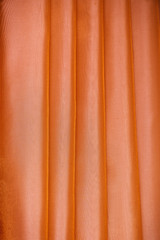 Vertical folds on orange organza curtains for background and design