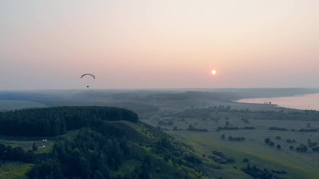 The sun is setting while the paraplane is floating in the sky. Parachute, paragliding comcept.