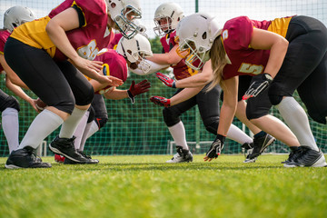 Photo of athletes women wearing helmets playing american football on sports field