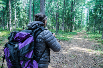 A man with a large tourist backpack traveling through the woods, ecotourism concept.