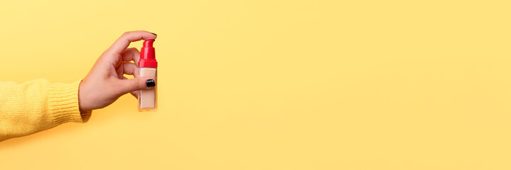 foundation in hand over yellow background, concept of skin problems, beige concealer for makeup, panoramic mock up