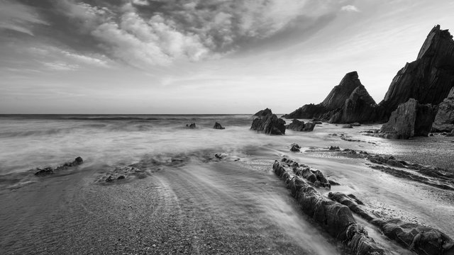 Stunning black and white sunset landscape image of Westcombe Beach in Devon England