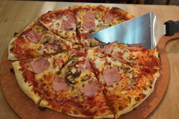 freshly made pizza with a spatula for serving. fast food, junk food, food on the go. vegetables and meat based with sauce.