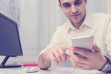 Male uses smart phone, man working in the office, front view