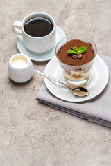 Classic tiramisu dessert in a glass, cup of espresso coffeeand cream on concrete background