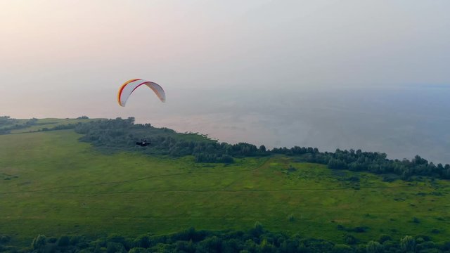 Green plain and a ram-air parachute gliding above it