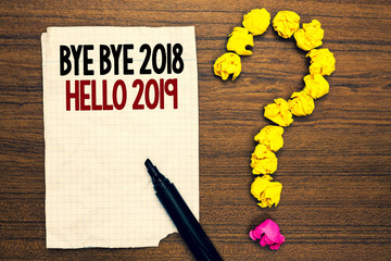 Word writing text Bye Bye 2018 Hello 2019. Business concept for Starting new year Motivational message 2018 is over Written torn page touch black pen yellow paper lob form question on woody deck © A