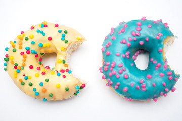 Blue and yellow donuts, two bitten donuts with bright sprinkles on a isolated background, food concept