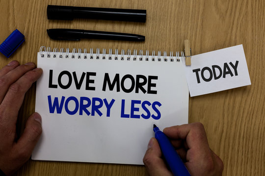 Word writing text Love More Worry Less. Business concept for Have a good attitude motivation be lovable enjoy life Hand hold pen notepad with words paperclip grip note paper woody base black pen