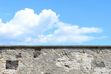 weathered stone castle wall with blue sky and cloud