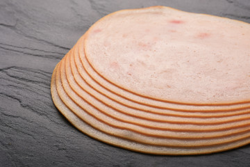 Smoked slices ham on black stone serving plate