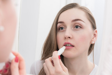 Attractive woman, looks in the mirror, using lipstick, morning routine, close up