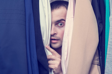 Scared man, naked lover hiding in the closet with clothing, portrait, close up, secret lovers concept