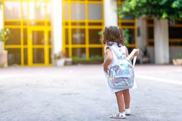 Back to school. Cute child girl with holographic backpack running and going to school with...