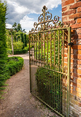 Rusty wrought iron gate opening into walled garden England