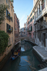 Fototapeta na wymiar Venice winter mysterious romantic: Gondola sailing with parsimony between the canals, crossing under bridges