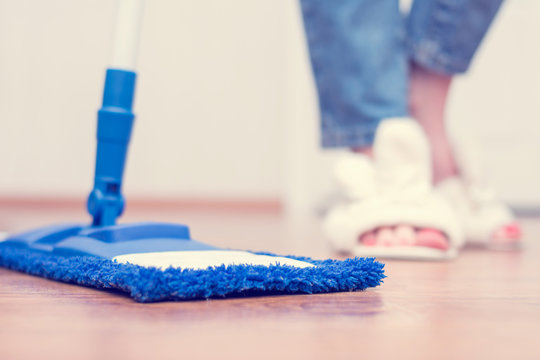 Woman washes the floor, flat wet-mop, cleaning her house, women's legs, close up, cropped image