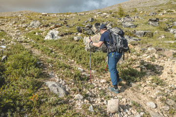 Man Hiking with backpack during the ascent of the peak in the summer. Concept trekking trips and active life with nature