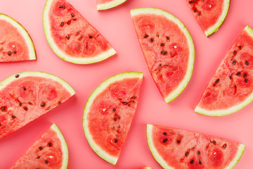 Juicy slices of red watermelon on a bright pink background. Conceptual colors of summer. Patterns top view as a background or substrate - obrazy, fototapety, plakaty