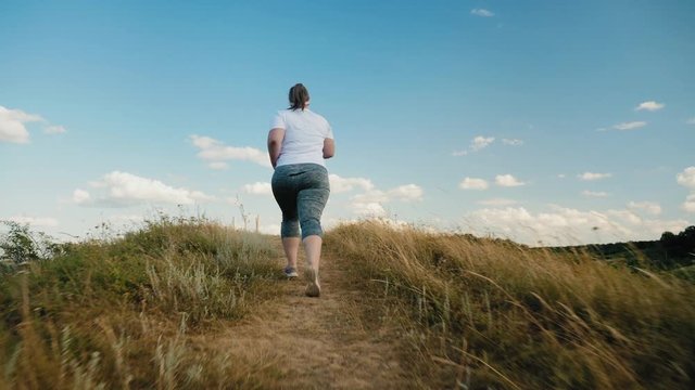 Back view overweight girl runs up the hill