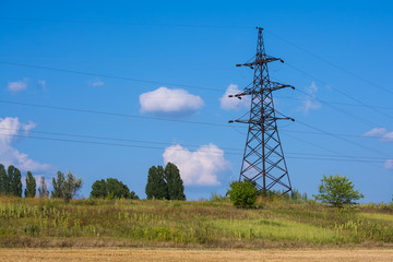 A large electric pole on a hill. Electric pylons. Electricity business. Thick wires. High voltage....
