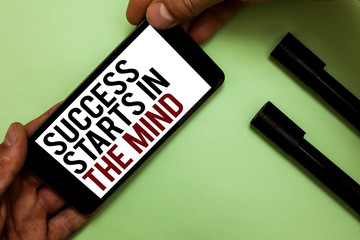 Text sign showing Success Starts In The Mind. Conceptual photo Have positive thoughts accomplish what you want Man's hand hold iPhone with black and red words near two black marker