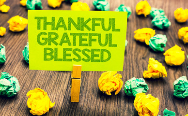 Handwriting text Thankful Grateful Blessed. Concept meaning Appreciation gratitude good mood attitude Paperclip retain written words yellow paper paper lobs laid on wooden floor