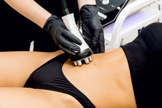 The doctor performs radiofrequency lifting on a woman to lose weight. Cosmetic hardware procedures and massage for weight loss. Beautiful slender woman undergoing the procedure