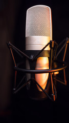 silver studio condenser microphone, isolated on black. with amber light	