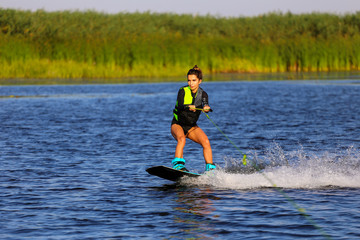 Young Sexy girl Catch waves on wakeboard when boat pulls a wakeboard 