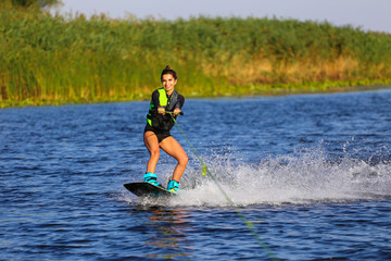 Young Sexy girl Catch waves on wakeboard when boat pulls a wakeboard 