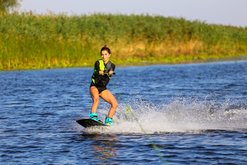 Young Sexy girl Catch waves on wakeboard when boat pulls a wakeboard 