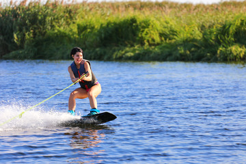 Happy girl riding on wakeboard at sunny day , smiling and happy 