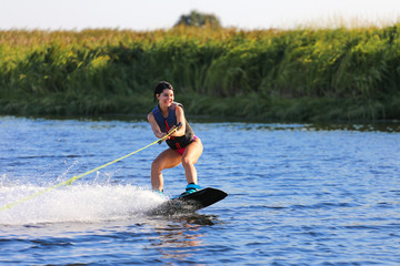 Happy girl riding on wakeboard at sunny day , smiling and happy 