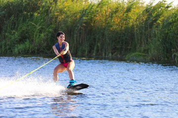 Happy girl riding on wakeboard at sunny day , smiling and happy 