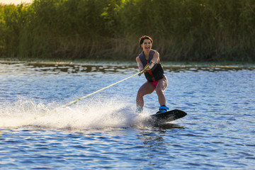 Happy girl riding on wakeboard at sunny day , smiling and happy 