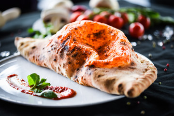 tasty italian calzone pizza with fresh ingredients and vegetables