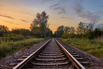 Fototapeta na wymiar Train tracks in front of nature and the beautiful sunset sky