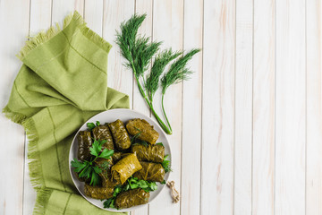 Delicious stuffed grape leaves (traditional doom Mediterranean cuisine Dolma) on a black plate with fresh cilantro and dill