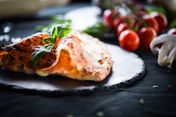 Schilderijen op glas smakelijke Italiaanse Calzone-pizza met verse ingrediënten en groenten © Anna_Anny
